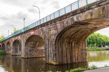 Saarbrucken Almanya 'sında üzerinde kırmızı-beyaz işareti olan eski bir köprü. Köprü bir nehrin üzerinde ve mavi beyaz bir korkuluğu var.