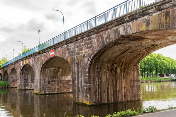 Saarbrucken Almanya 'sında üzerinde kırmızı-beyaz işareti olan eski bir köprü. Köprü bir nehrin üzerinde ve mavi beyaz bir korkuluğu var.