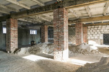 Duvara dayanmış merdiveni olan büyük boş bir oda. Oda tuğladan yapılmış ve zeminde çok fazla kir var.