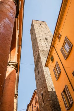 İtalya 'nın Bologna şehrindeki antik taş kuleler. Gökyüzü açık mavi ve hafif bulutlu. Fotoğraf komşu evlerin parçalarını gösteriyor..