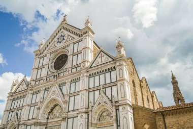 Floransa 'da büyük beyaz bir kilise. Önünde mavi bir haç olan İtalya Toscana. Bina tuğla bir duvarla çevrili.
