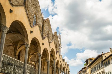 İtalya 'nın Floransa şehrinde çok kemerli bir Gotik bina. Gökyüzü mavi ve bulutlu.