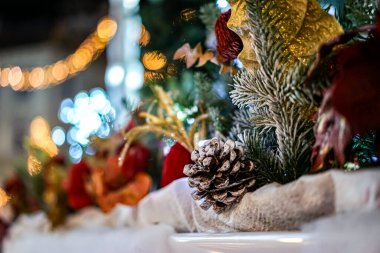 Akşam ışığında Noel motifi, çam kozalağı ve başka aksesuarların olduğu yerde. Arka planda bulanık ışıklar var..