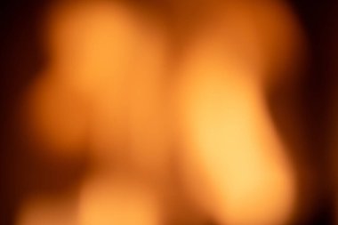 Arkaplan sarı ve turuncu tonlarda bulanık ve siyah kenarlı. Arka planda bulanık bir ateş ya da fener var..