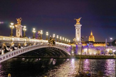 Akşamları Alexander Köprüsü 3 'te. Fotoğraf akşam geç saatlerde köprünün ışıkları açıkken çekilmişti. Invalides 'in evi arka planda görünüyor..