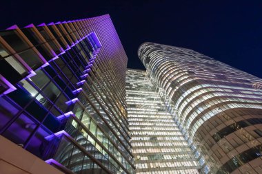 Paris 'in La Defense bölgesindeki yüksek binaların gökdelenleri. Fotoğraf akşam geç saatlerde çekildiği için binanın pencereleri ışıklandırılmış. Gökyüzü koyu ve koyu mavi.