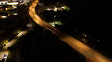 Şehir manzarasının uzun pozlu gece çekimleri geçen arabalardan ve aydınlık gökdelenlerden gelen parlak ışık izlerini yakar, gece gökyüzüne karşı dinamik ve parıldayan bir şehir manzarası yaratır..