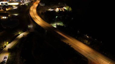 Şehir manzarasının uzun pozlu gece çekimleri geçen arabalardan ve aydınlık gökdelenlerden gelen parlak ışık izlerini yakar, gece gökyüzüne karşı dinamik ve parıldayan bir şehir manzarası yaratır..