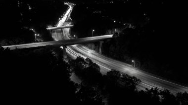 Şehir manzarasının uzun pozlu gece çekimleri geçen arabalardan ve aydınlık gökdelenlerden gelen parlak ışık izlerini yakar, gece gökyüzüne karşı dinamik ve parıldayan bir şehir manzarası yaratır..