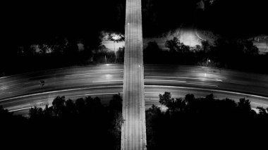 Şehir manzarasının uzun pozlu gece çekimleri geçen arabalardan ve aydınlık gökdelenlerden gelen parlak ışık izlerini yakar, gece gökyüzüne karşı dinamik ve parıldayan bir şehir manzarası yaratır..