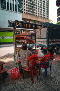 Vietnam 'da bir sokak yemeği standında oturan iki kadın, şehrin hayat dolu sokaklarında sakin bir anı paylaşıyorlar..