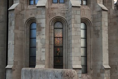 A close-up view of stained glass windows on a church facade, with intricate patterns reflecting on the surface of the building. clipart