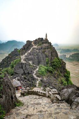 Dik taş basamaklar Mua Mağaraları 'na kadar uzanır, Ninh Binh manzarasının kireçtaşı dağları ve yemyeşil yeşillikleri ile panoramik görüntüsünü sunar..