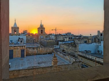 Sunrise over the rooftops and bell towers in Valletta, Malta, casting a warm glow over the historic architecture. clipart