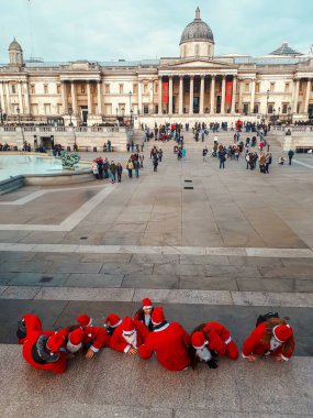 Group of people dressed as Santa Claus gathered on the steps in Trafalgar Square, London, with the National Gallery in the background. clipart