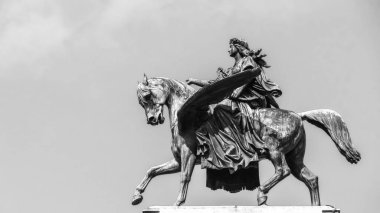 Black and white photo of a horse statue with a winged figure, symbolizing power and grace.