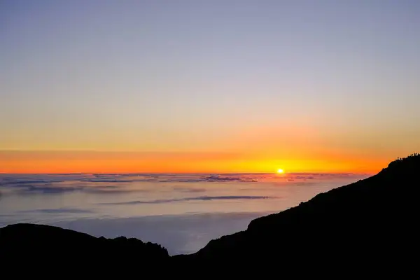 Pico do Arieiro, Madeira - Okyanus üzerinde gün doğumunun çarpıcı bir görüntüsü. Yükselen güneşin ılık renkleri gökyüzünü turuncu, sarı ve mor renkte aydınlatır..