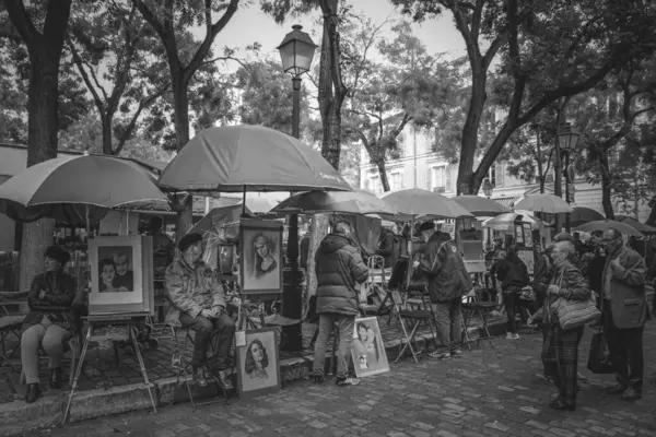Şemsiyeler altında satılık portreleri olan sanatçılar, Paris 'te bir sokak sahnesini çekiyorlar, siyah beyaz fotoğraflar çekiyorlar..