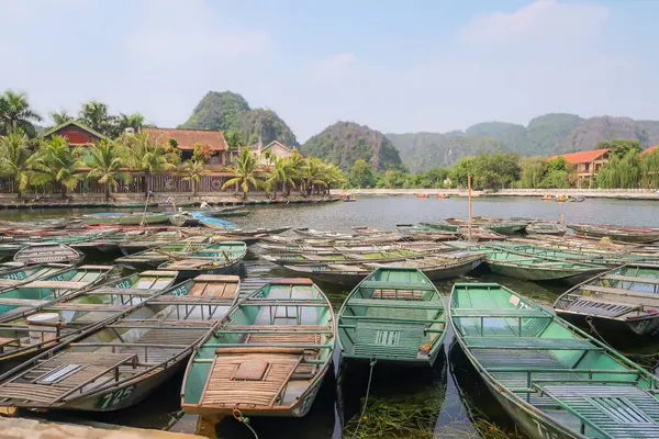 Vietnam rıhtımında turistler için geleneksel yeşil botlar. Bereketli yeşilliğin, dağların ve sakin suların tropik bir ortamda manzarası.
