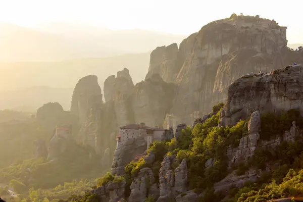 Günbatımında çarpıcı Meteora kaya oluşumları, yemyeşil ve dramatik dağ manzaralarıyla çevrili antik manastırların tepede tünediği yer.