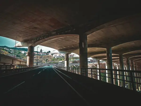 Yapıyı destekleyen beton kolonlar ile Santa Cruz Havalimanı pistinin altından manzarayı izleyin, Madeira.