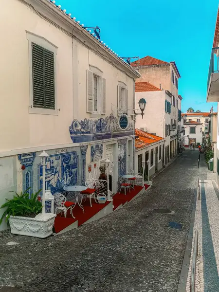 Madeira 'da bir kafede mavi azulejo döşemeleri ve açık hava koltukları olan hoş bir kaldırım taşı caddesi..