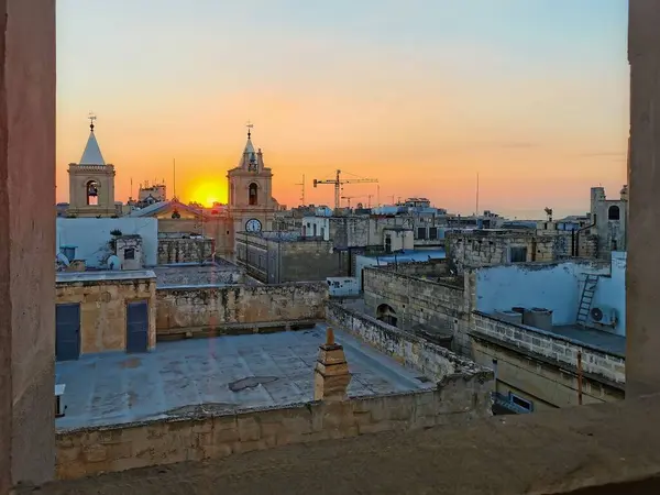 Malta Valletta 'daki çatı ve çan kuleleri üzerinde gün doğumu, tarihi mimarinin üzerine sıcak bir ışık saçıyor..