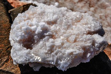 Beyaz tuz kristalleri güneş ışığında bir kayanın üzerinde doğal geometrik bir yapı oluşturur..