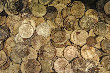 Çeşitli ülkelerden gelen eski gümüş ve bronz sikkeler daha yakından görülüyor. Yaş ve oksitlenme belirtileriyle klasik para biriminin karışımı..