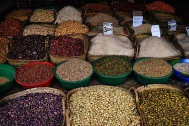 Bir açık hava pazarında sepetlerde ve plastik kaselerde sergilenen tahıl, fasulye ve pirinç çeşitleri.
