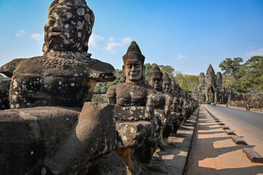 Angkor Thom 'un güney kapısında, Kamboçya' daki Angkor kompleksinin bir parçası olan köprüde taş heykeller asılıdır.