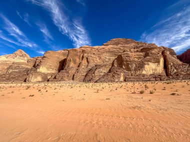 Wadi Rum çölündeki kum taşı uçurumları, Ürdün, ince bulutlu mavi gökyüzünün altında.