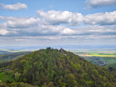 Üzerinde Saint Barbara Şapeli olan yeşil ormanlık bir tepenin manzarası, bahar manzarası ve dramatik bulutlu gökyüzü ile çevrili. Çek Cumhuriyeti 'nin Buchlov Kalesi yakınlarında çekildi.