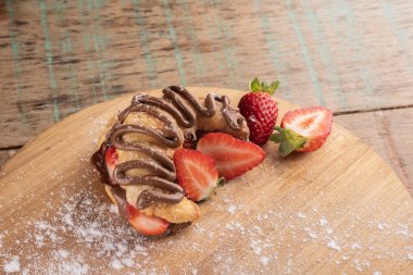 Çilekli fındık kremalı kruvasan. Köy masasındaki ahşap bir tahtanın üzerinde.