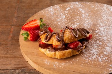 Fındık kremalı kruvasan tatlısı. Ön taraftaki ahşap masada çilekli.