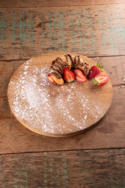 Fındık kremalı kruvasan tatlısıyla çilekli ahşap tahta üzerinde köy masasının köşesinde bistro üst manzarasında.