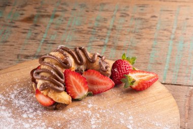 Fındıklı kremalı kruvasan tatlısı ve ahşap tahtada çilek.