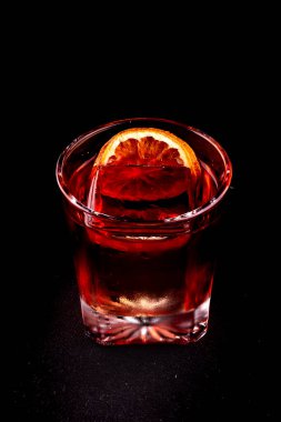 Negroni Campari. Profesyonel şeffaf buzlu siyah tutucu portresi.