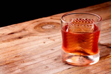 Negroni içeceği, ahşap masa üzerinde dalgalı profesyonel kabuklu buz, karanlık arka plan.