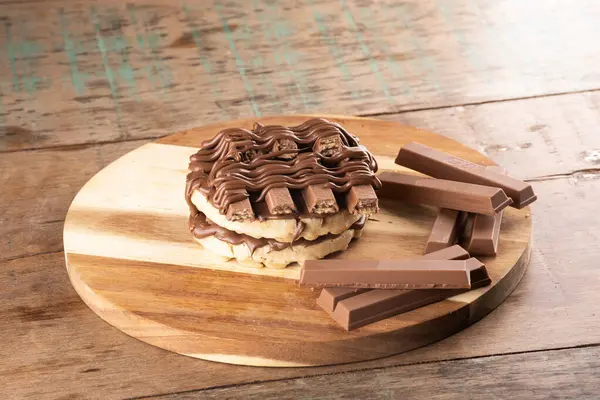 double waffle with chocolate coating on chocolate bars on rustic wooden table in FRONT angle