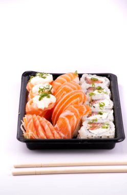 Sushi teslimat tepsisi beyaz arkaplanda izole edilmiş ve yemek çubukları yakın plan portrede.