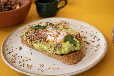 Sağlıklı protein kahvaltısı, domatesli tost, avokado, rafadan yumurta, meyveli yoğurt ve maydanozlu tahıl gevreği.