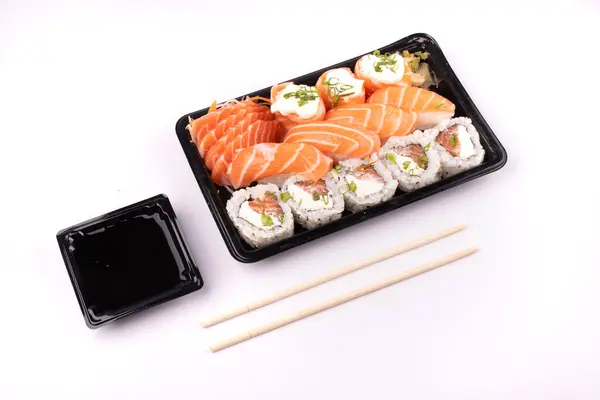 Japon yemeği suşi teslimatı arka planda izole edilmiş beyaz arka planda yemek çubukları ve soya sosu ile açılı.
