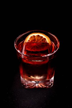 Negroni Campari. Profesyonel şeffaf buzlu siyah tutucu portresi.