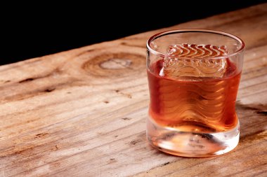 Negroni içeceği, ahşap masa üzerinde dalgalı profesyonel kabuklu buz, karanlık arka plan.