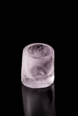 Siyah zemin üzerinde buzdan yapılmış shot bardağı.
