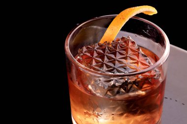 Şeffaf kristal buz, bir bardak portakal kabuklu negroni içeceği için büyük dalgalı.