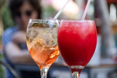 Meydanda kokteyl bardaklarını kapatın. Ortasında kırmızı ağaçlar ve arka planda bulanık bistro masasında rosatto olsun.