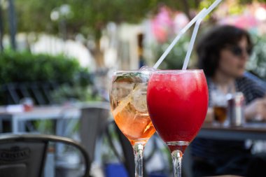 Meydanda kırmızı ve rosatto ağaçlarının olduğu bir meydanda kokteyl bardaklarını bir bistro masasında kapatın.