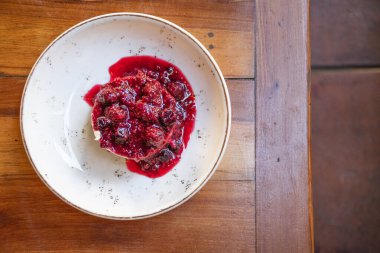 Lokanta masasının üstünde çilek reçelli leziz cheesecake tatlısı.